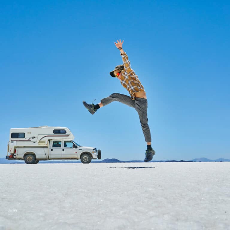 Bolivia, Salar de Uyuni, boy jumping at camper on salt lake