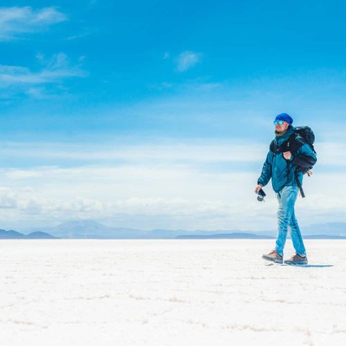 Tourist with equipment and camera walking in sunshine Salar de Uyuni